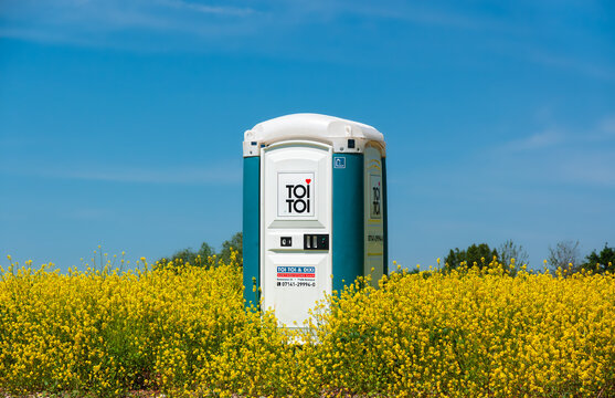 Konstanz, Germany - May 15, 2022: TOI TOI provides toilet infrastructure with mobile toilets for celebrations, concerts, sporting events and construction sites. Mobile toilet on the  rapeseed field.
