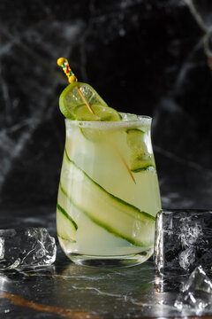 Gin gimlet cocktail garnished with cucumber. Green alcohol cocktail. With a cucumber on a black background.