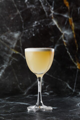 Pisco sour cocktail - whiskey with lime, egg white, sugar syrup in glass on dark blurred background. Space for text