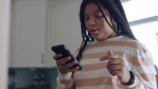 Black teenage girl holds phone, listing ingredients, memorizing steps, chatting