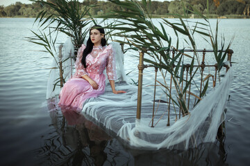 a girl sits on a bed in a pink dress in the water
