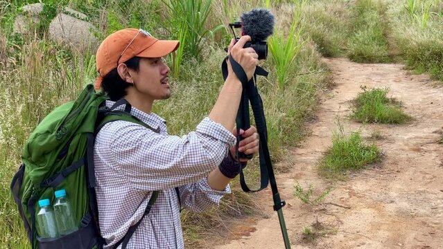 Backpacker vlogger traveling in the forest. Attractive use camera record video vlog, Hiking in nature forest with happiness during holiday vacation trip
