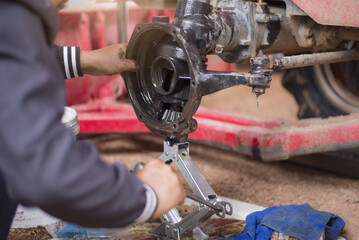 Mechanic repairing tractor axle, close to axle.