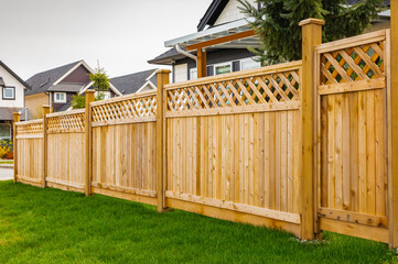 Nice wooden fence around house. Wooden fence with green lawn. - Powered by Adobe