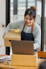 Startup small business SME. young Asian entrepreneurs using laptop computer check online orders and prepare to pack for customers. Successful SME business online concept.