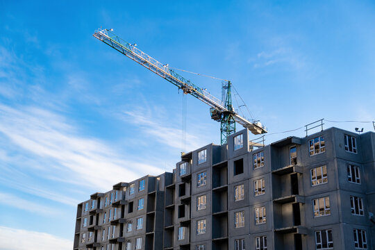 Construction crane over an unfinished residential building. Housing construction, apartment building in the city
