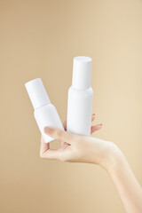 Front view of hand model holding cosmetic jar in beige background for cosmetic advertising