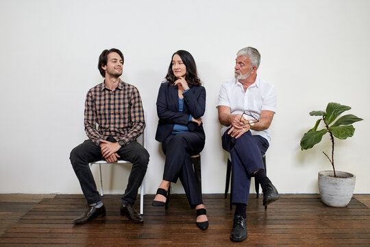 Three professional business people sitting in a row in a studio