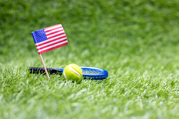 Tennis ball and racket with flag of America on green grass for 4th July Independence Day