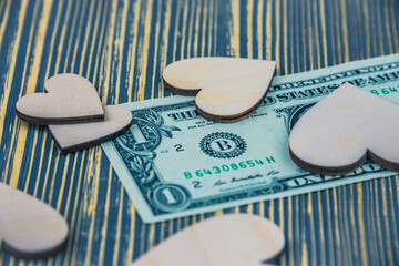Dollar and heart on a wooden table, concept: love of money.