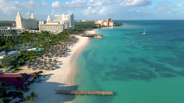 Palm Beach Aruba, Amazing tropical beach with palm trees entering the ocean against azur ocean, gold sand, and blue sky. 