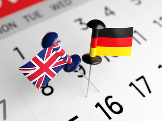 English and German flags are pinned on a white-colored calendar page. Horizontal composition. Focused image.