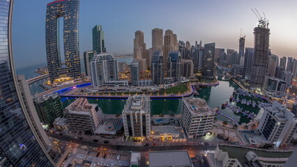 Naklejka premium Panorama of Dubai Marina with several boats and yachts parked in harbor and skyscrapers around canal aerial night to day timelapse.
