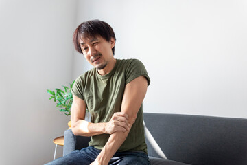 Portrait of mature Asian man have elbow pain, pressing on elbow joint with painful expression,...