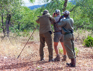 Three men in protective camouflage clothing on trophy hunt in Africa.
