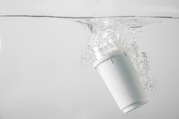 water filter dropped into the water on a white background