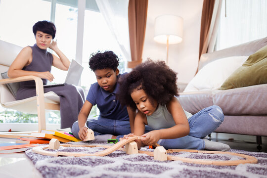 Family relaxing and playing in living room. African American little kid boy and girl playing toys