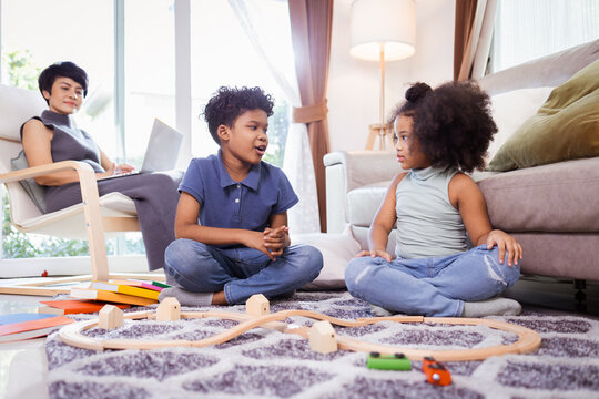 African American little kid boy and girl having fun while playing toys in the living room on floor