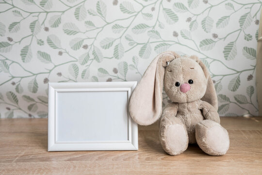 Portrait white picture frame mockup on wooden table with toy rabbit