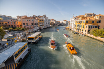View on Grand Canal with vaporetto and gondolas in Venice. Venetian water transportation concept. Idea of traveling Italy. Cityscape in autumn sunny day - obrazy, fototapety, plakaty
