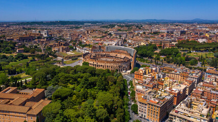 Obraz premium Aerial view of Colosseum and the Arch of Titus, in Italy, on a sunny day. These monuments of ancient Rome are a symbol of the city and visited by many tourists every day.