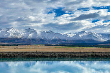 Snowcovering the Ben Ohau range with the blue blue water of the Pukaki canal in the foreground