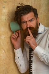 Man listening through the wall with the cup. Secrets and gossip concept. Curious guy overhearing...