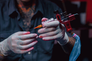 Tattoo artist hands hold a Tattoo Machine in the tattoo studio. Tattoo artist preparing to made a...