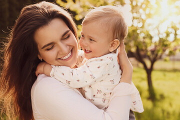 Happy mother with her cute baby in park on sunny day