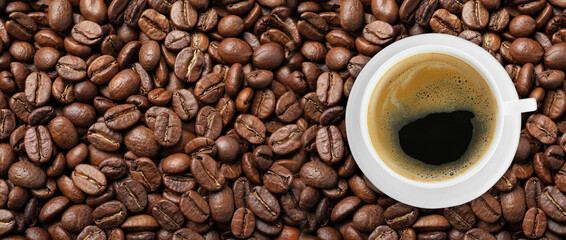 Cup of tasty aromatic coffee on roasted beans, top view. Banner design - obrazy, fototapety, plakaty