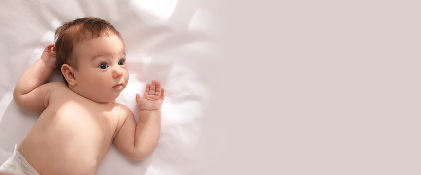 Cute little baby on bed, top view with space for text. Banner design