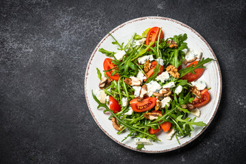 Arugula salad with tomatoes and blue cheese at black.