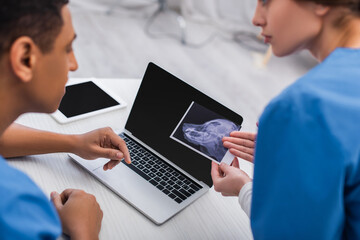 Blurred multiethnic veterinarians working with ultrasound scan of animal in clinic