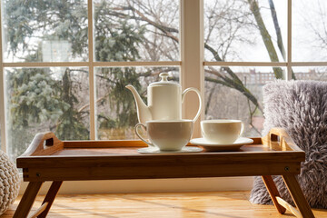 Cup of coffee on the window sill. In the background, a beautiful winter landscape in snow. Cozy home concept