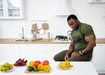 Strong lifestyle person indoor on kitchen. Healthy athletic man eating apple.