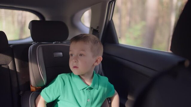 A boy in a child car seat while traveling. The child goes on a summer trip.