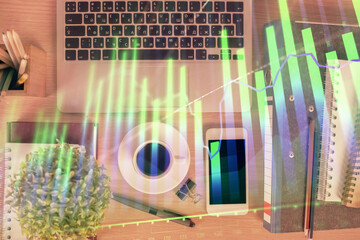 Double exposure of financial graph hologram over desktop with phone. Top view. Mobile trade...