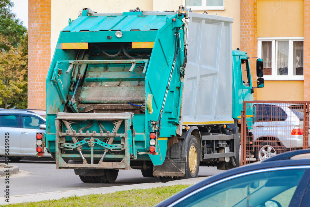 Leinwandbilder A garbage truck picks up garbage in a residential area. Loading mussar in containers into the car. Separate collection and disposal of garbage. Garbage collection vehicle.