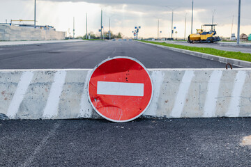 A stop road sign and concrete blocks block the entrance to the construction site. Closed road....