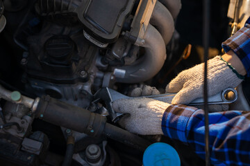 Fototapeta premium Close-up hands of auto mechanic are using the wrench to repair and maintenance auto engine is problems at car repair shop. Concepts of car care check and fixed and services insurance.