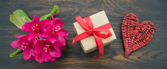 Mothers day card hand with heart and gift on brown wooden background.