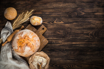 Fresh bread and buns at rustic wooden table.