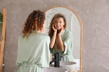 Beautiful woman looking at herself in bathroom mirror