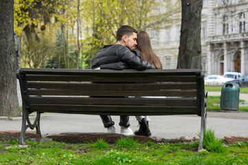 Fototapeta premium Lovely young couple on bench outdoors, back view. Romantic date
