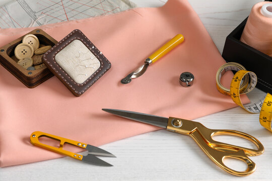 Set of sewing supplies and accessories with fabric on white wooden table