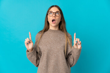 Young Lithuanian woman isolated on blue background surprised and pointing up
