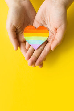 International Day Against Homophobia, Transphobia and Biphobia. May 17. Stop Homophobia. Heart with rainbow LGBT flag in the hands on yellow background.