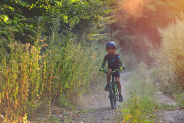 Happy kid boy of 8 years having fun in autumn park with a bicycle on beautiful fall day. Active...