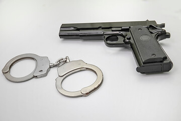 Handgun And Handcuffs. Isolated.Black handgun and handcuffs flat on a white background. Copy Space. Stock Image.