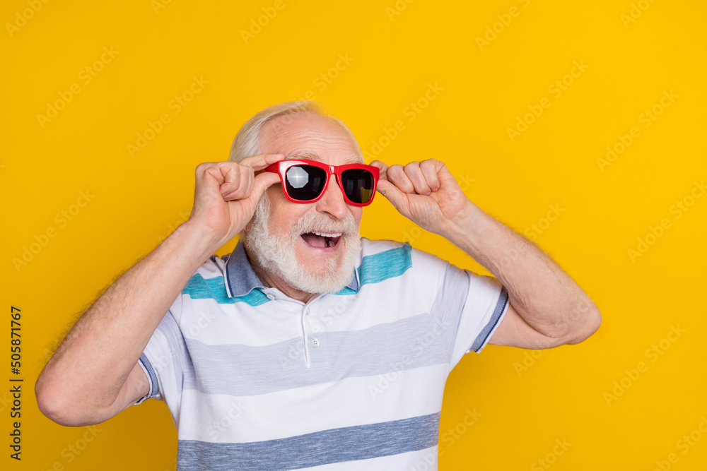 Poster portrait of attractive funny dreamy cheerful grey haired man touching specs having fun isolated over